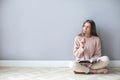 Young woman with notepad think hard sitting on a wooden floor