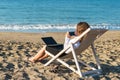 Young woman in office clothes with a laptop on the beach on a background of the sea in a summer sunny day. Concept Royalty Free Stock Photo