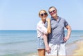 A young woman and an older man are laughing and hugging on the seashore on a sunny day. Adult daughter and father travel and relax Royalty Free Stock Photo