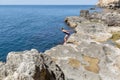 Young woman in one-piece swimsuit resting on rocky seashore Royalty Free Stock Photo