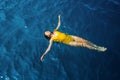 Young woman in a one-piece yellow swimsuit floats on the surface of the water.