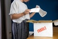 Young woman opening damaged delivery package,online shopping package. Broken fragile plate at home