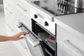 Young woman opening electric oven in kitchen Royalty Free Stock Photo