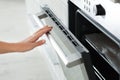 Young woman opening electric oven in kitchen Royalty Free Stock Photo