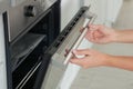 Young woman opening electric oven in kitchen Royalty Free Stock Photo