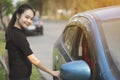 Young woman opens door of blue metallic car