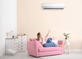 Young woman operating air conditioner with remote control Royalty Free Stock Photo