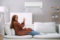 Young Woman Operating Air Conditioner Royalty Free Stock Photo