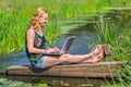 Young woman operating laptop near water in nature Royalty Free Stock Photo