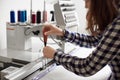 Woman operator making adjustments in modern computerized embroidery machine using screwdriver.