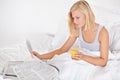 Young woman, orange juice and reading newspaper on bed for headlines, energy and health body with wellness. Blonde Royalty Free Stock Photo