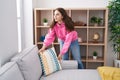 Young woman organizing sofa standing at home