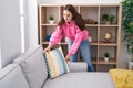 Young woman organizing sofa standing at home