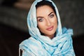 Young woman of oriental appearance in a blue scarf. Beauty portrait of arabian or indian girl with perfect makeup