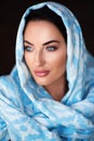 Young woman of oriental appearance in a blue scarf. Beauty portrait of arabian or indian girl with perfect makeup