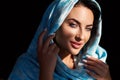 Young woman of oriental appearance in a blue scarf. Beauty portrait of arabian or indian girl with perfect makeup Royalty Free Stock Photo