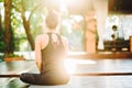 Young woman with oriental appearance practicing yoga samakonasana alone on wooden deck in tropical island. Girl doing