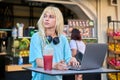 Young woman in outdoor cafe with fruit fresh juice using laptop Royalty Free Stock Photo