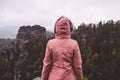 Young woman in outdoor clothing standing alone in front of jugged mountain top ridge with wild forest in the valley in Royalty Free Stock Photo