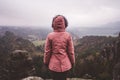 Young woman in outdoor clothing standing alone on mountain top with wild forest in the valley in background. Travel Royalty Free Stock Photo