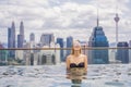 Young woman in outdoor swimming pool with city view in blue sky. Rich people Royalty Free Stock Photo