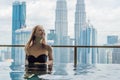 Young woman in outdoor swimming pool with city view in blue sky Royalty Free Stock Photo