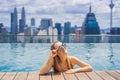 Young woman in outdoor swimming pool with city view in blue sky Royalty Free Stock Photo