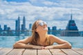 Young woman in outdoor swimming pool with city view in blue sky Royalty Free Stock Photo