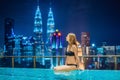 Young woman in outdoor swimming pool with city view at night Royalty Free Stock Photo