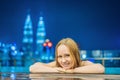 Young woman in outdoor swimming pool with city view at night Royalty Free Stock Photo