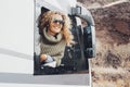 Young woman outside the window of her modern camper van motor home enjoy arrival travel destination admiring the outdoors. Concept