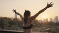 Young woman outstretched arms and standing in the city at sunset