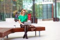 Young woman over a coffee break using laptop outside modern office buildings Royalty Free Stock Photo