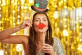 Young woman over gold background with photo booth accessories