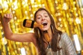 Young woman over gold background with photo booth accessories