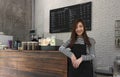 Young woman owner of a cafe stand in front of coffee counter, yo