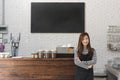 Young woman owner of a cafe stand in front of coffee counter, yo