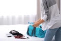 Young woman packing sports stuff for training into bag in bedroom