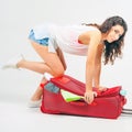 Young woman packs her things, clothes at full luggage