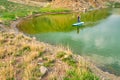 Young woman on paddle board SUP at lake Iacobdeal, Romania, paddling near the shoreline, on tranquil, pristine waters, at sunset