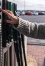 A young woman with painted nails and a nice sweater, manipulates some buttons of a gas pump in a service station Royalty Free Stock Photo