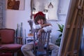 Young woman, painter, designer and artist with a red beret, sitting on a chair upside down and leaning on the backrest, brushes in Royalty Free Stock Photo