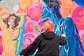 Young woman painter painting multicolored picture on large canvas, outdoor art performance festival