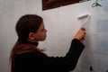 Young woman painting bathroom ceramic wall tiles ,do it your self ,renovation
