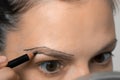 Young woman is painting contour of eyebrows using pencil before painting them. Royalty Free Stock Photo