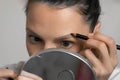 Young woman is painting contour of eyebrows using pencil before painting them. Royalty Free Stock Photo