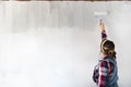 Young woman painting new apartment walls in color white with paint roller. Renovating house