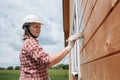 A young woman paints the outside wall of a new wooden house