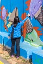 A young woman paints a picture with a color spray on a concrete security fence on the border between Israel and Lebanon.