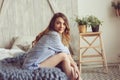 Young woman in pajama wake up in the morning in cozy scandinavian bedroom and lying on bed with oversize knitted blanket Royalty Free Stock Photo